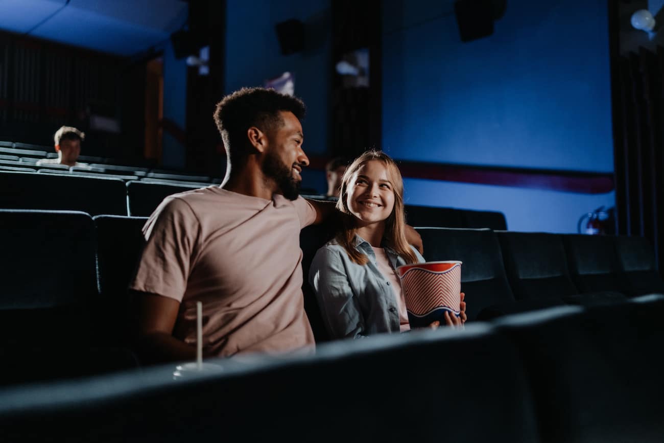 cheerful young couple in love in the cinema, watching film.